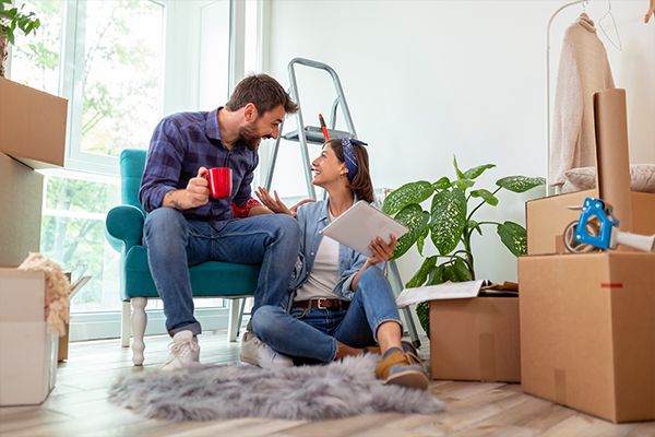 Pareja joven sentada entre cajas de mudanza, planificando su nueva hipoteca para su primera vivienda.